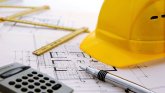 Gebäudemanagement Stadtpläne mit Taschenrechner und Schutzhelm