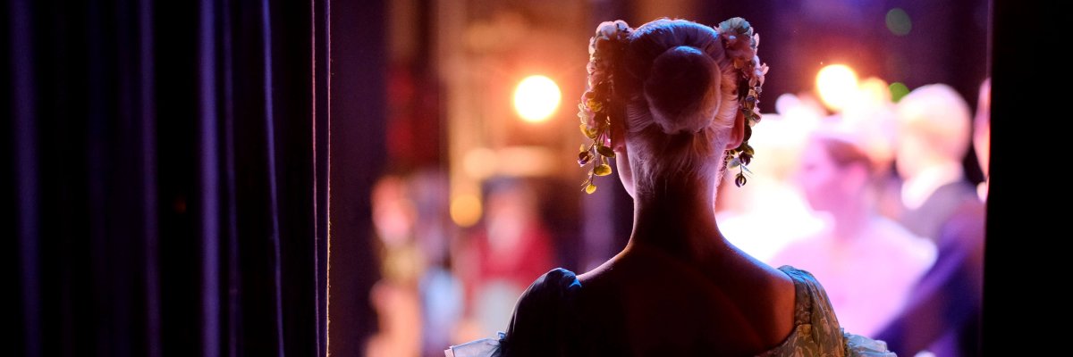Theater & Kultur Blick auf Bühne mit Rückansicht einer Schauspielerin